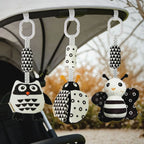 Set of three black and white high-contrast sensory toys hanging from a pram stroller bar for on-the-go visual stimulation, available from Senso-Blanky