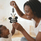 Mother holding up a high-contrast ladybug visual toy during tummy time encouraging newborn baby to reach and build motor skills, available from Senso-Blanky